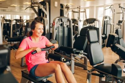 A woman completing a virtual challenge for Teenage Cancer Trust using a rowing machine in her gym