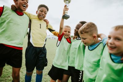 Primary school aged children celebrating winning a sporting tournament which raised money for Teenage Cancer Trust