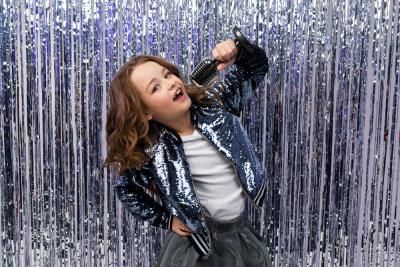 A girl singing into a microphone as part of a talent contest to raise money for Teenage Cancer Trust