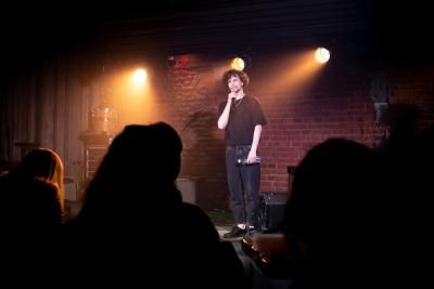 A stand up comedian on stage at a comedy night to raise money for Teenage Cancer Trust