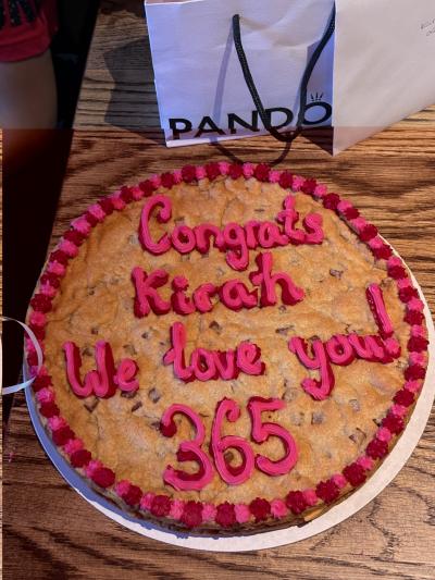 Kirah's congratulations cake for being out of a coma for 365 days. The cake is decorated with pink and red icing which circles the perimeter of the cake. There is also pink icing text which reads: Congrats Kirah. We love you! 365.