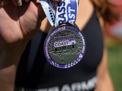 Participant holds up silver and purple challenge medal