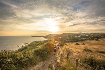 Participants walk along the coast as the sun sets