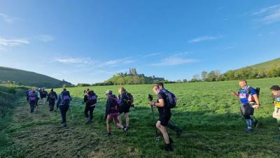 Participants walk through fields past Corfe Castle