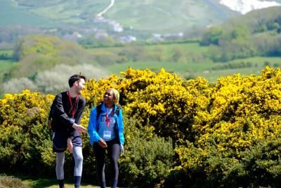 Two participants climb a hill surrounded by gorse