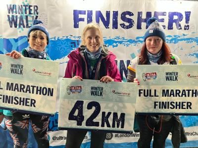 Challenge finishers hold signs which read '42km' and 'Full Marathon Finisher'