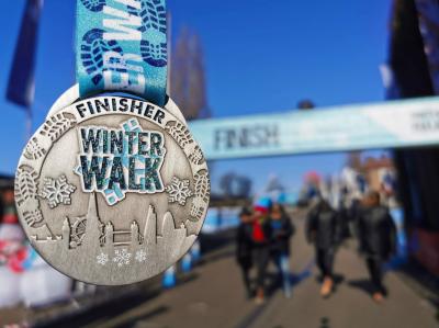 London Winter Walk medal held up in front of the finish line