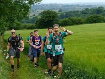 Challenge participants smile while climbing a hill in the Surrey countryside