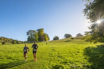 Participants run down a hill in the sunshine