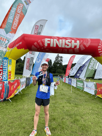 Participant holds up medal at the finish line