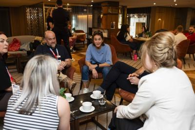 Vicky McLure - a woman with dark hair wearing a pale blue sweater - sits talking to five young people