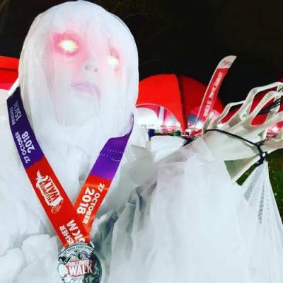 Participant dressed as a spooky ghost wearing their medal