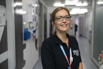 Teenage Cancer Trust Nurse standing in hospital corridor smiling